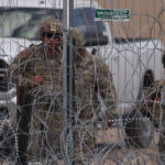 Personal de la Guardia Nacional estadounidense permanecen junto a una cerca de navajas y púas en el muro fronterizo entre México y EEUU en Ciudad Juárez, Chihuahua. Foto de EFE/ Luis Torres.