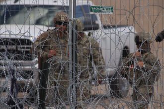 Personal de la Guardia Nacional estadounidense permanecen junto a una cerca de navajas y púas en el muro fronterizo entre México y EEUU en Ciudad Juárez, Chihuahua. Foto de EFE/ Luis Torres.