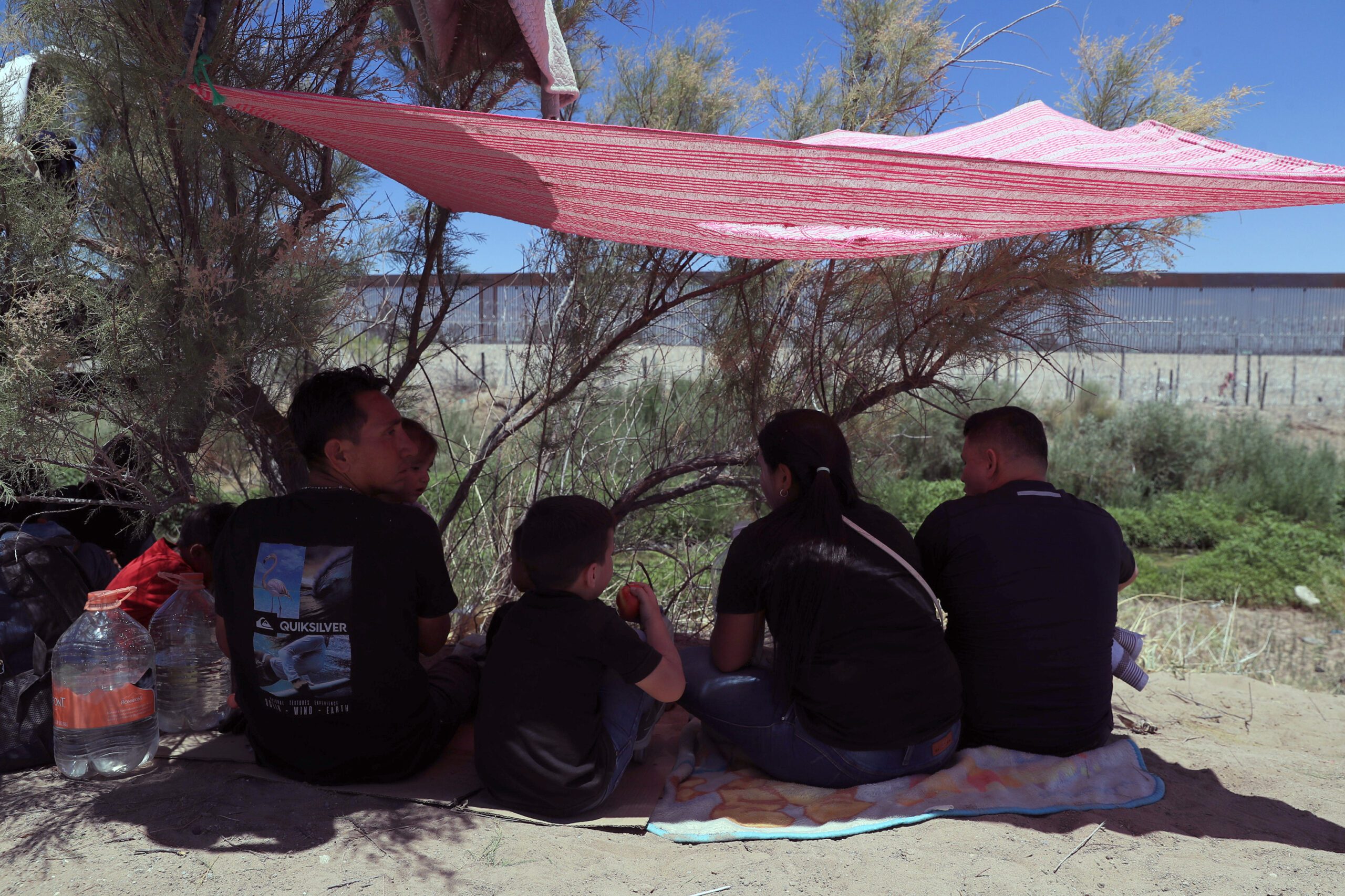 Migrantes que permanecen en un campamento, protegiéndose de las altas temperaturas debido a la tercera onda de calor en Ciudad Juárez. Foto de EFE/ Luis Torres
