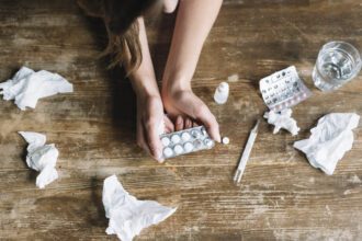 high angle view woman s hand holding blister pack wooden desk