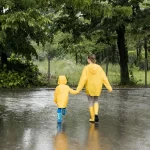 long shot mother son holding hands while wearing rain coats 1