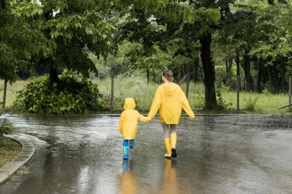 long shot mother son holding hands while wearing rain coats 1