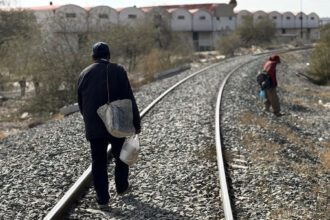 Migrantes caminan por vías de tren en Altar, Sonora. Foto de JLMNoticias / EFE/ Daniel Sánchez.