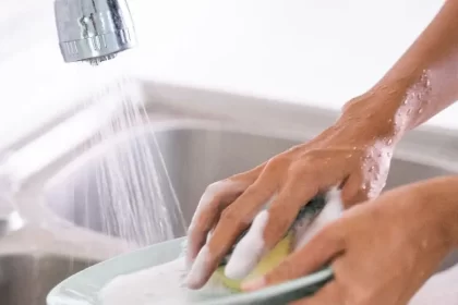 Persona lavando trastes con el agua desperdiciándose