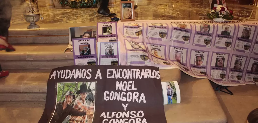 A los pies del altar el colectivo de madres buscadoras colocaron las fotografias de hijos y esposos desaparecidos