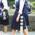 Estudiantes con uniforme escolar caminando en un plantel educativo.