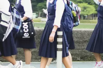 Estudiantes con uniforme escolar caminando en un plantel educativo.